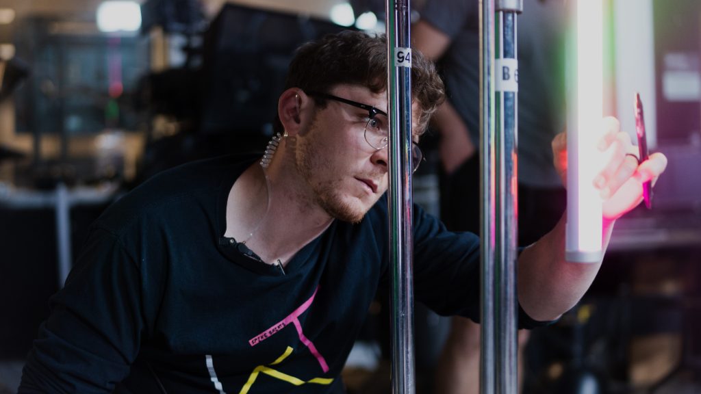 Crew member adjusting a coloured light panel on set