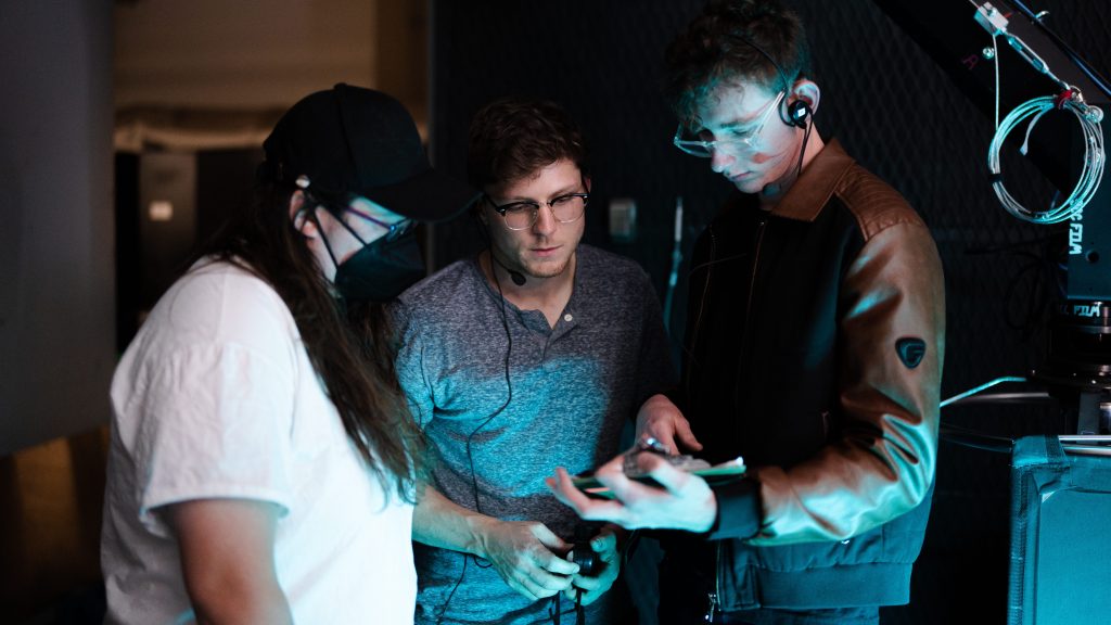 Three crew members gathered around a camera monitor