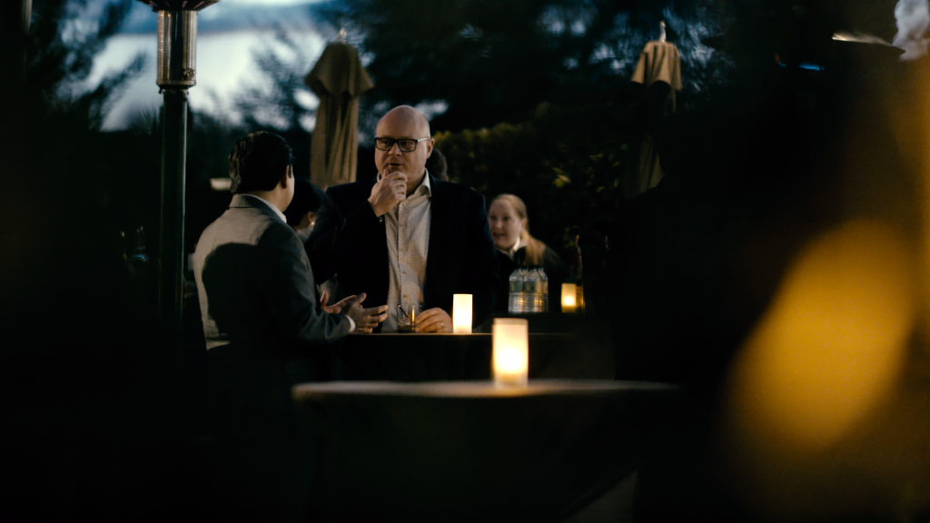 Three people at an outdoor table by candlelight