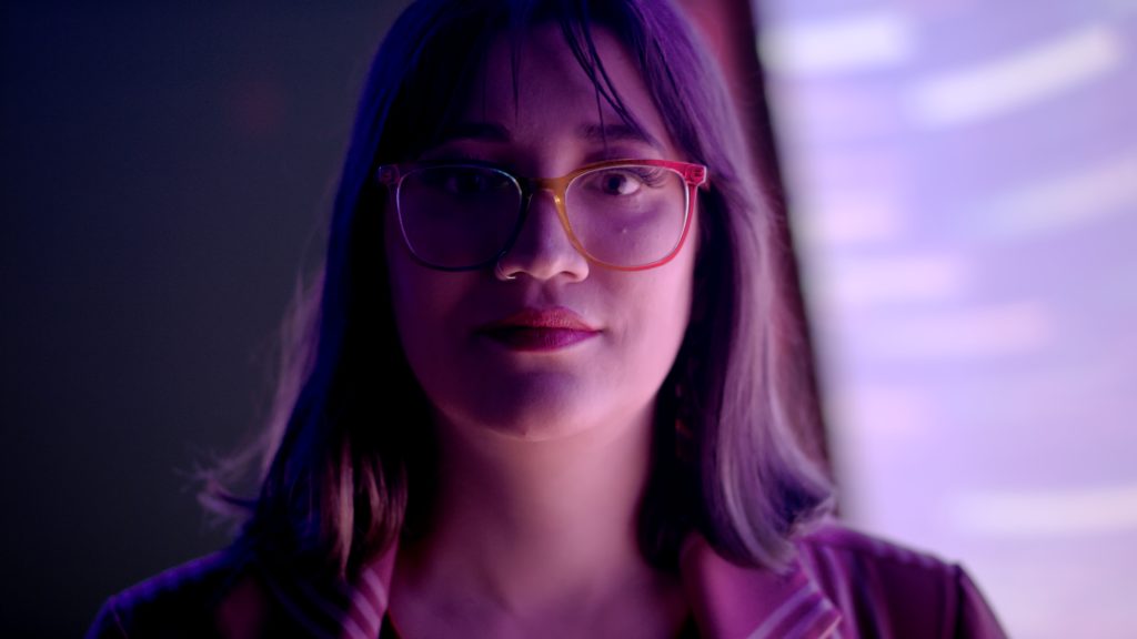 Portrait of a woman in glasses under purple neon light
