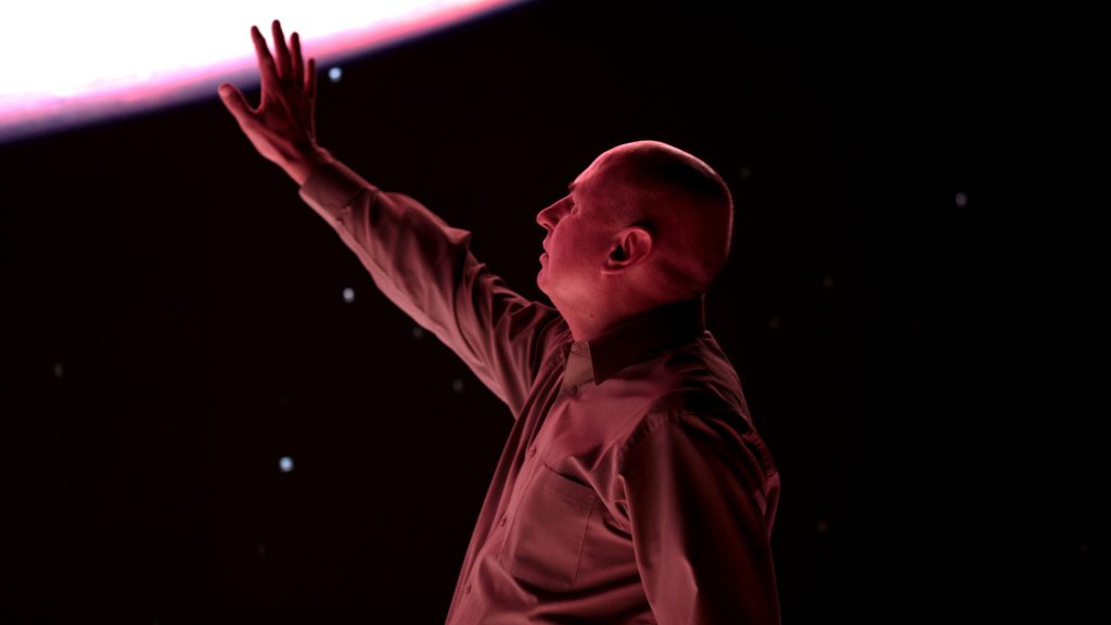 Man reaching upward against a deep red, starlit backdrop